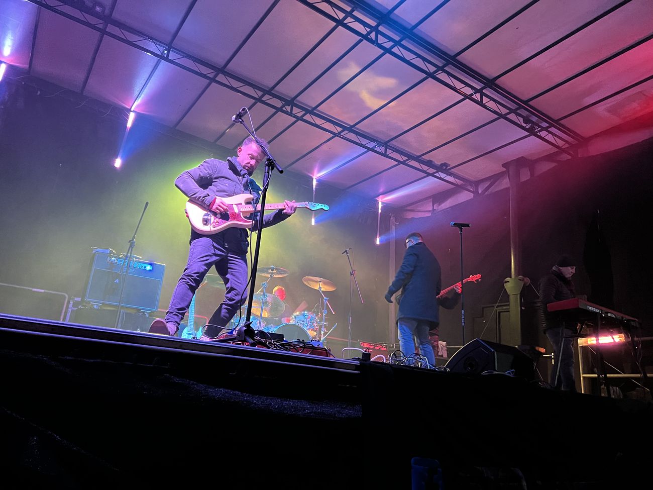 Rock band performing on night stage with purple haze lighting