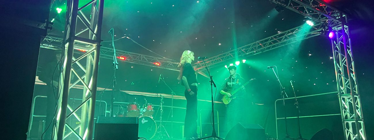 Band performing on stage with dramatic green and purple lighting