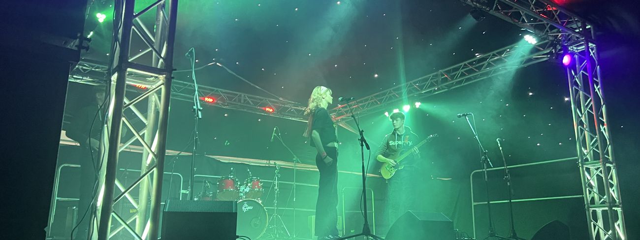 Band performing on stage with dramatic green and purple lighting