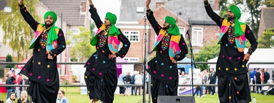 Bhangra dancers performing on outdoor stage at a festival