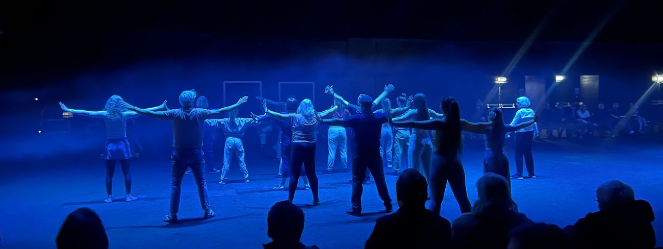 Dance troupe performing under blue stage lighting