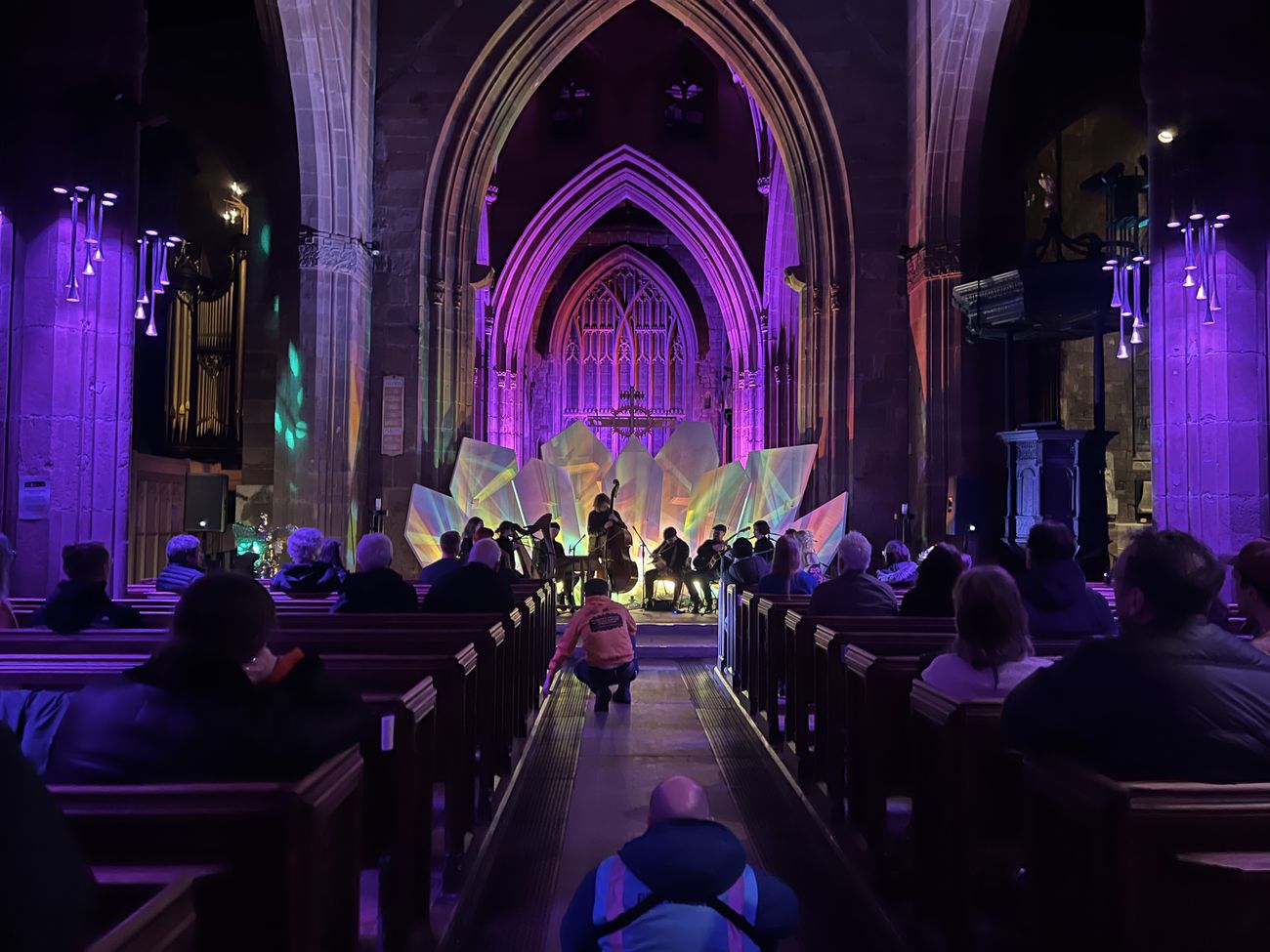 Concert audience in cathedral bathed in purple stage lighting