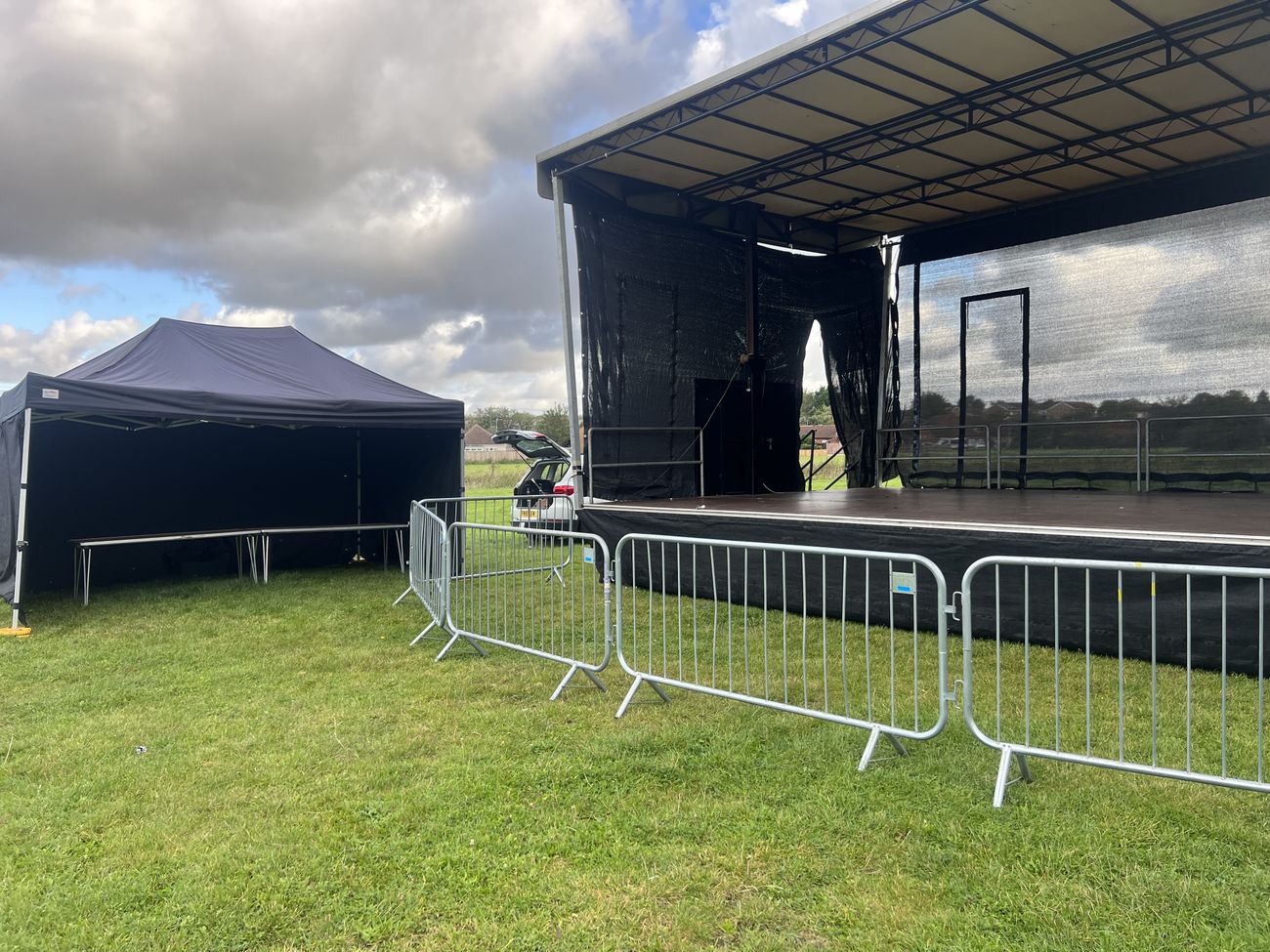 Outdoor stage with gazebo and crowd barriers at a fundraising event